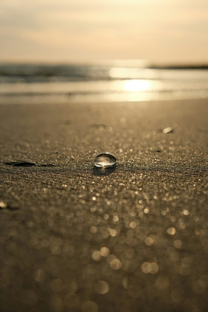 goûte d'eau sur le sable avec un coucher de soleil